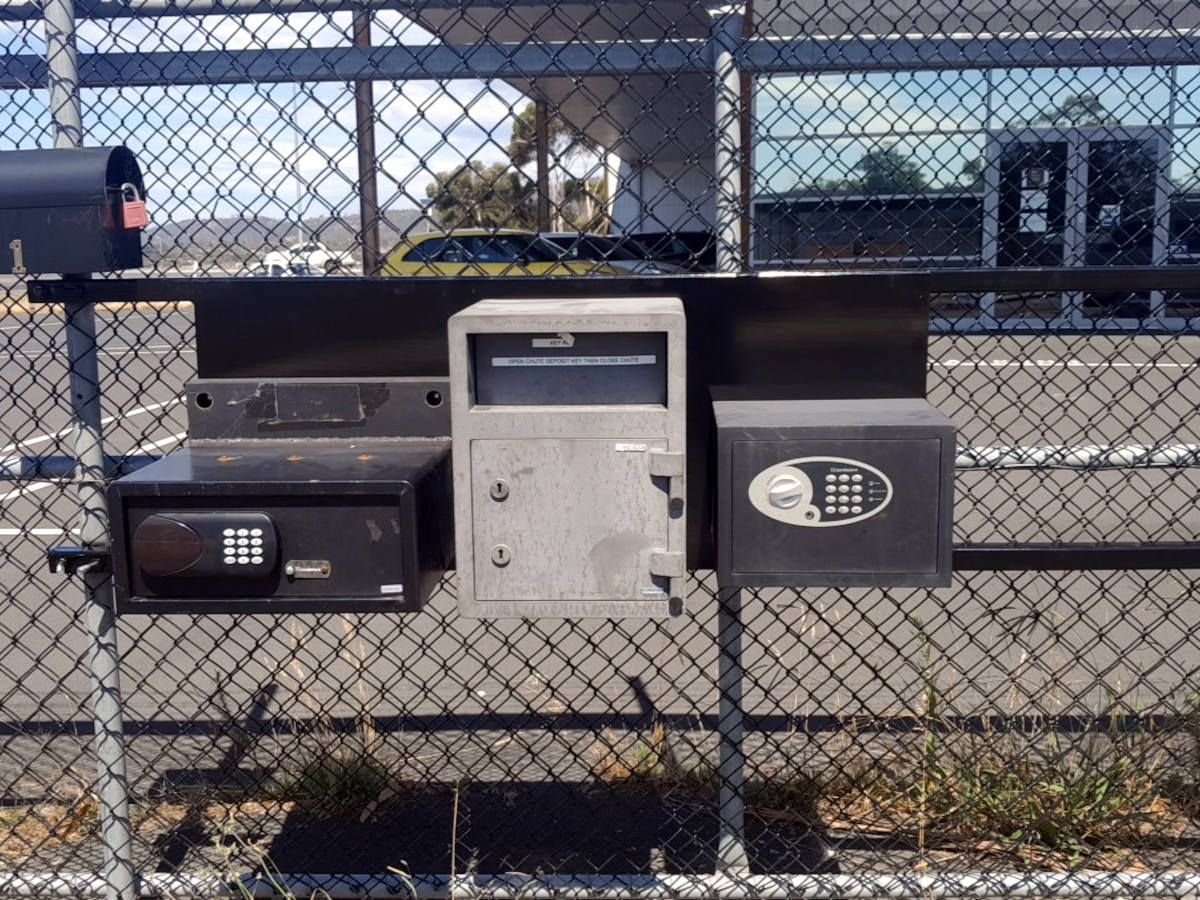 Fence with a range of mailboxes and key drop boxes on it